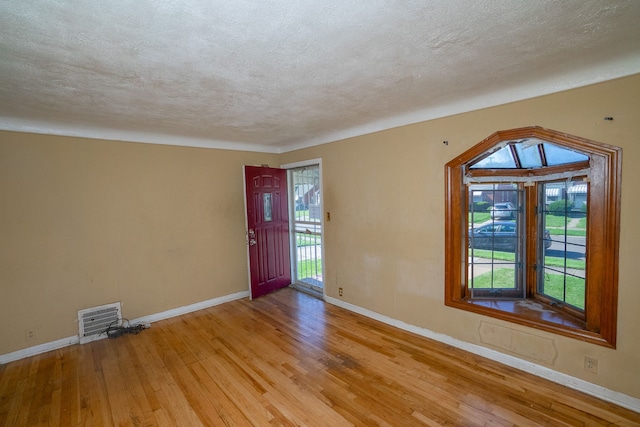 entrance foyer with visible vents, light wood-type flooring, a wealth of natural light, and baseboards