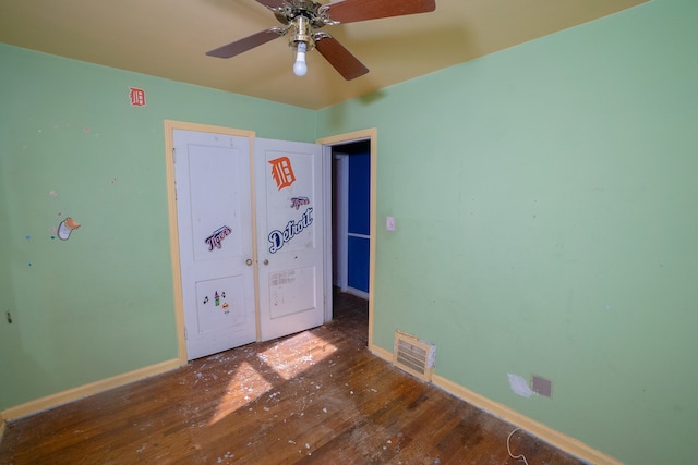 unfurnished bedroom featuring hardwood / wood-style flooring, baseboards, visible vents, and a ceiling fan