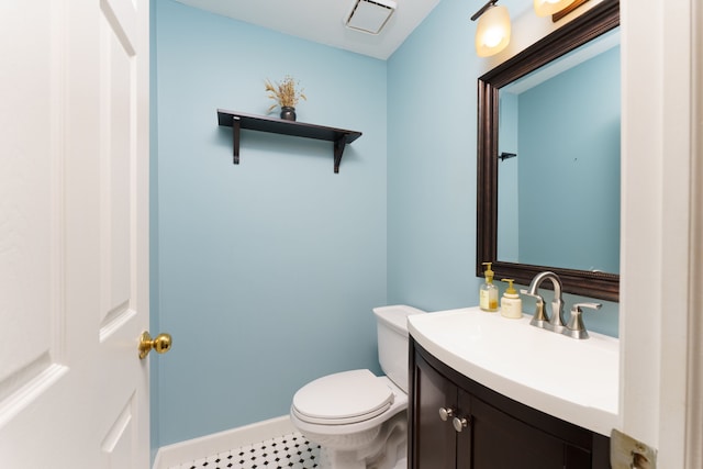 half bathroom with vanity, toilet, and baseboards