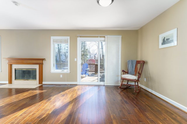 unfurnished room with a fireplace with flush hearth, baseboards, and wood-type flooring