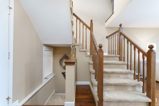 staircase featuring wood finished floors and baseboards