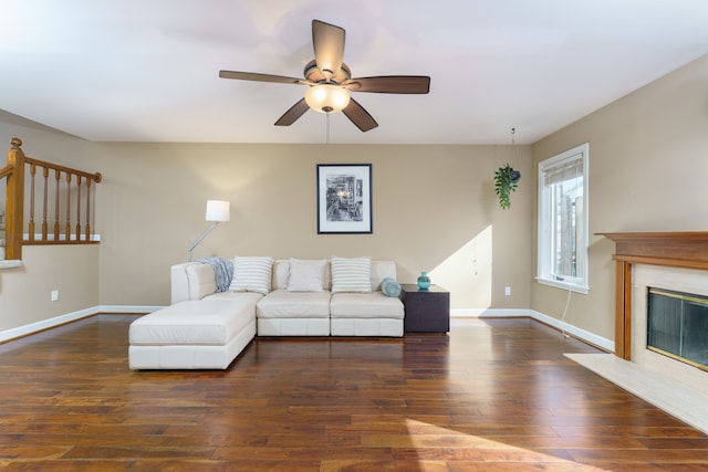 living area featuring hardwood / wood-style floors, a fireplace, baseboards, and ceiling fan