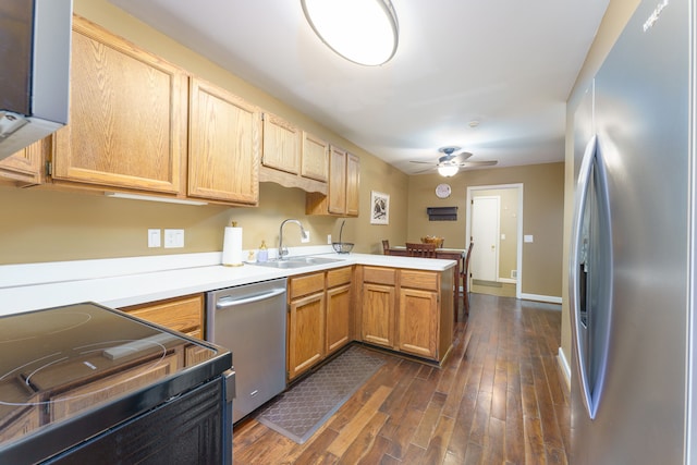 kitchen featuring a sink, light countertops, appliances with stainless steel finishes, a peninsula, and dark wood-style flooring