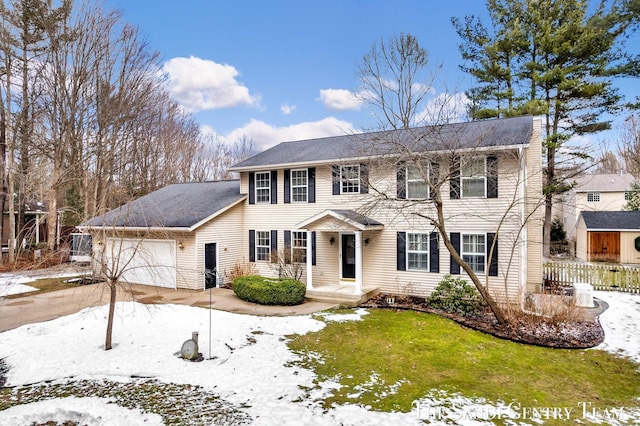 colonial-style house with driveway, an attached garage, and fence