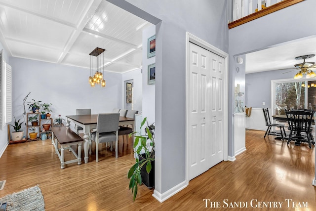 dining room with baseboards, coffered ceiling, wood finished floors, and ceiling fan with notable chandelier