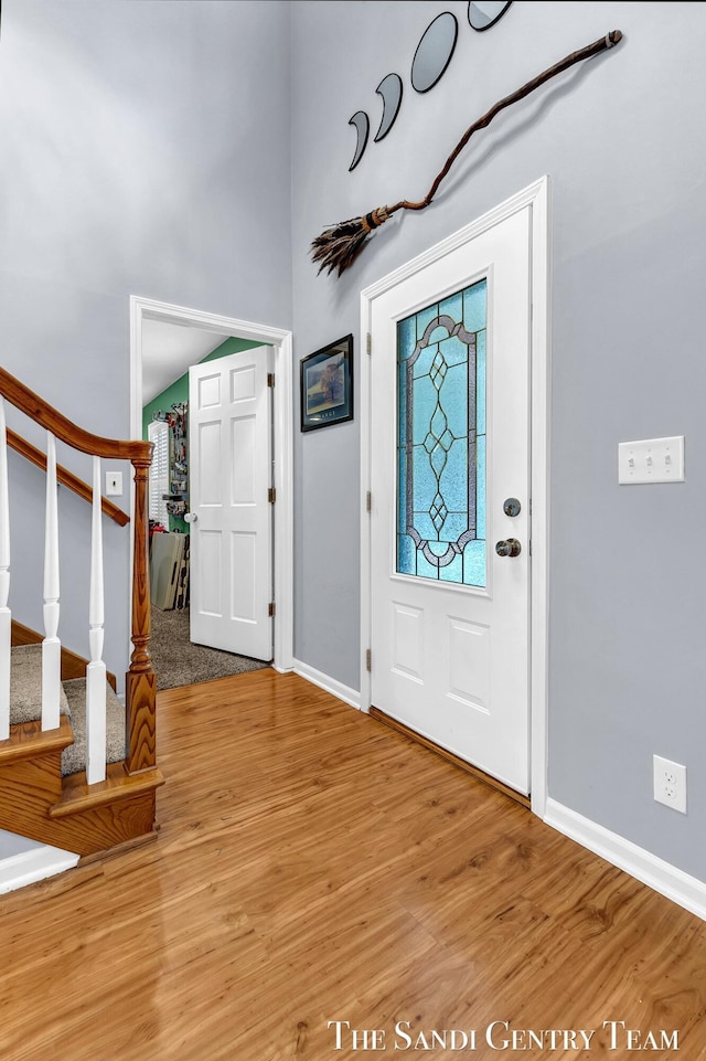 foyer entrance featuring stairway, baseboards, and wood finished floors