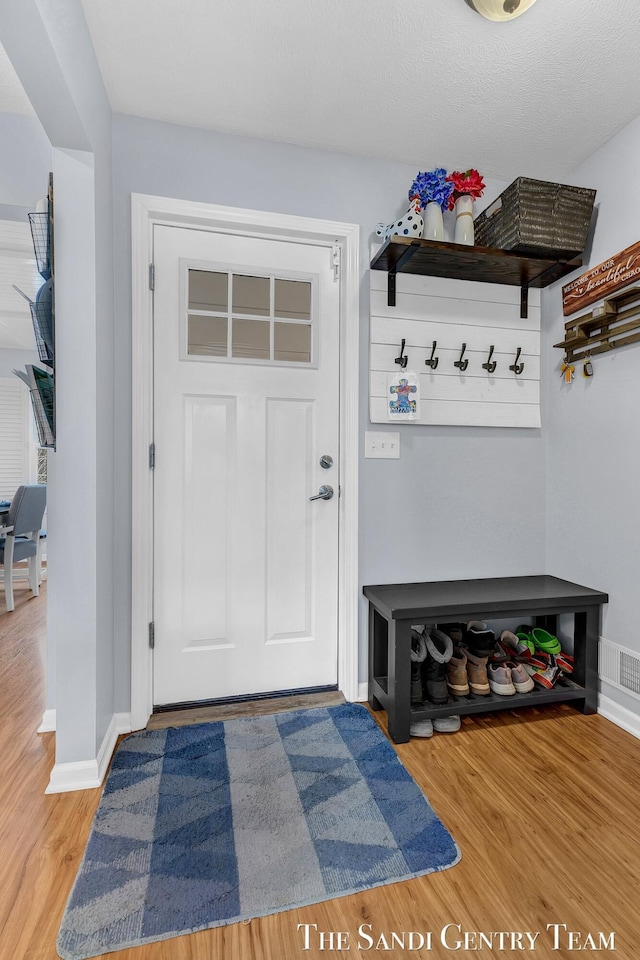 mudroom featuring wood finished floors, visible vents, and baseboards