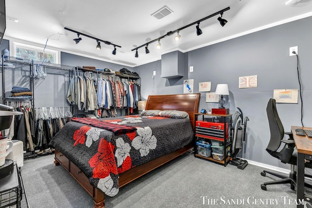 bedroom featuring carpet flooring, visible vents, baseboards, rail lighting, and crown molding