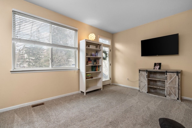 sitting room with carpet floors, visible vents, and baseboards