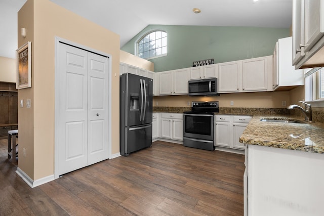 kitchen featuring stainless steel appliances, stone countertops, dark wood-type flooring, and a sink