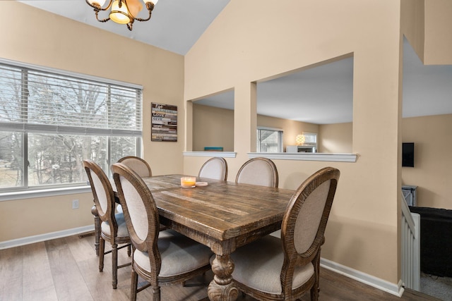 dining space with baseboards, a notable chandelier, and wood finished floors