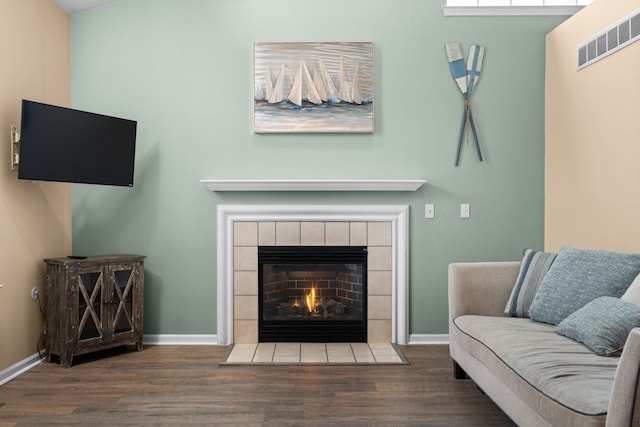 sitting room featuring a tiled fireplace, wood finished floors, visible vents, and baseboards