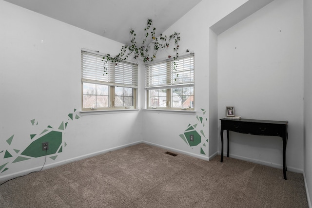 carpeted spare room featuring lofted ceiling, visible vents, and baseboards