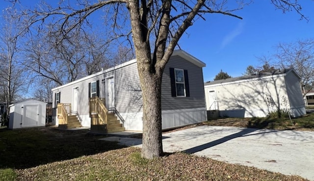 view of front of property with an outbuilding, concrete driveway, and a shed