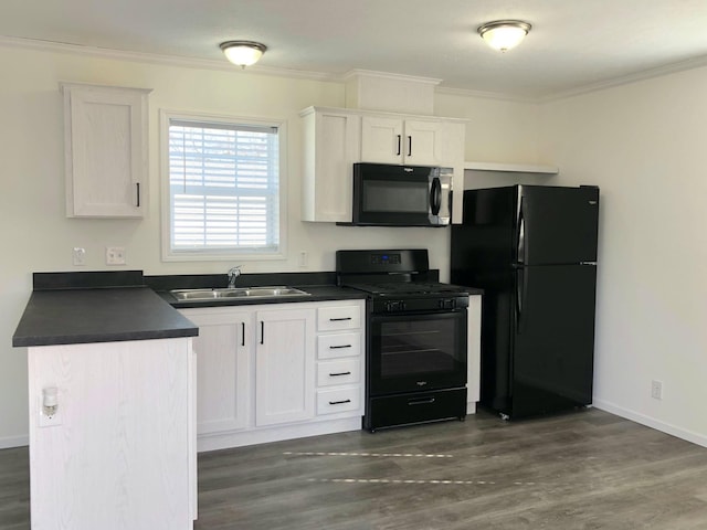 kitchen featuring black appliances, ornamental molding, dark countertops, and a sink