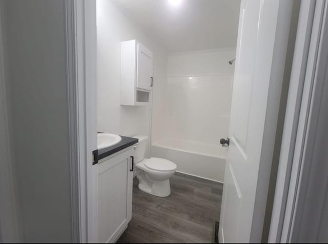 bathroom with toilet, shower / washtub combination, wood finished floors, and vanity