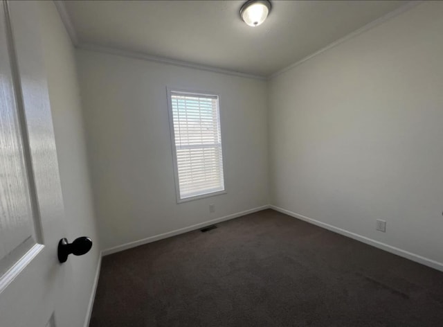 spare room with dark carpet, visible vents, crown molding, and baseboards