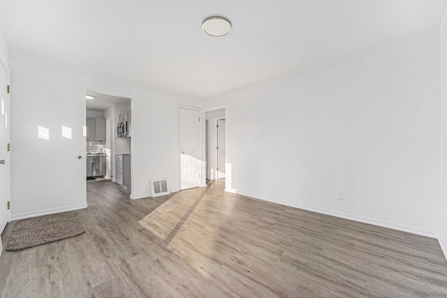 unfurnished living room with baseboards, visible vents, and wood finished floors