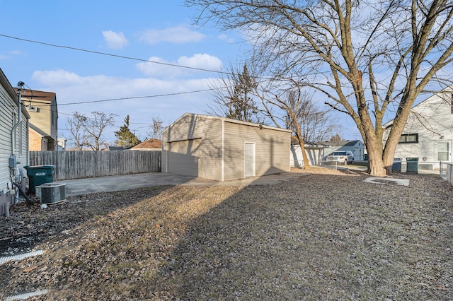 view of yard with a garage, central AC, an outbuilding, and fence