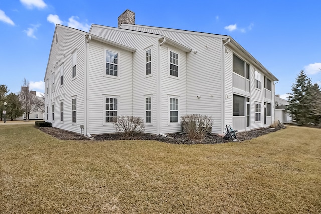 view of side of property featuring a chimney and a lawn