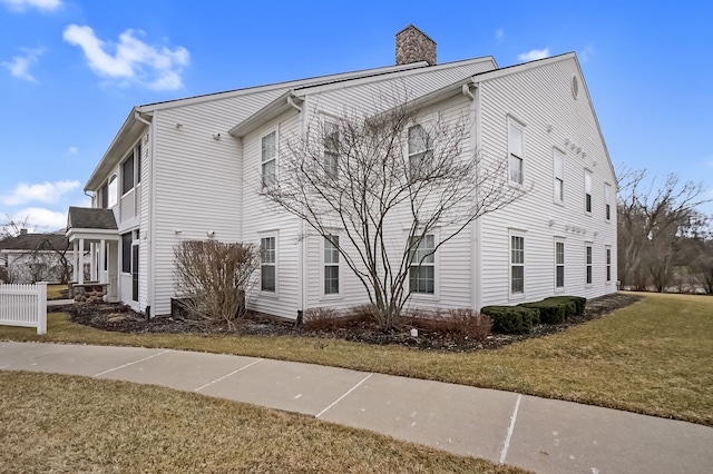 view of side of home with a yard and a chimney