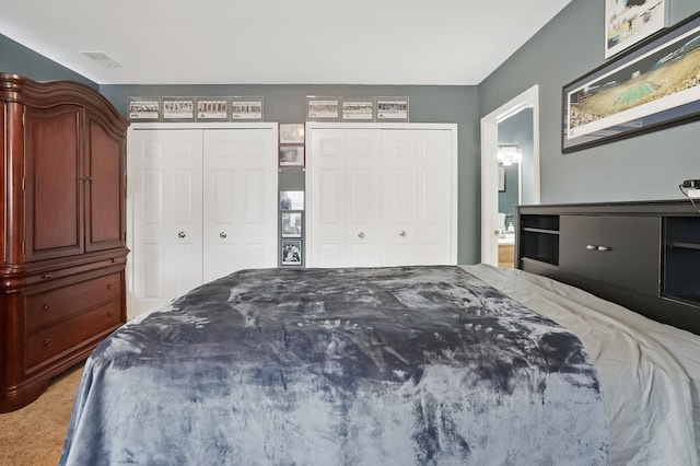 bedroom with light carpet and two closets