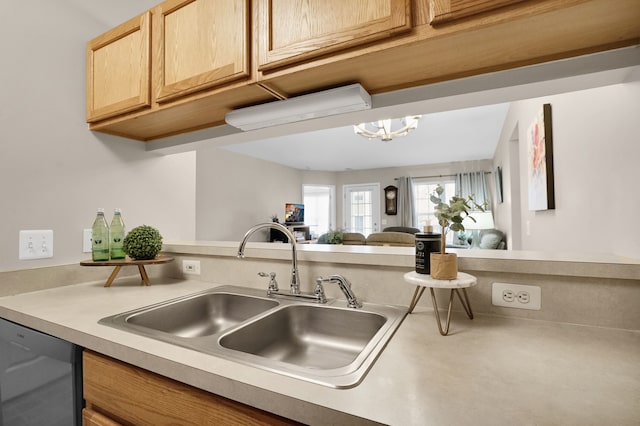 kitchen with dishwashing machine, a sink, open floor plan, light countertops, and light brown cabinetry