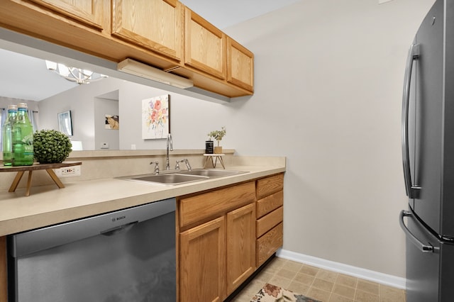 kitchen with stainless steel appliances, light countertops, a sink, and baseboards