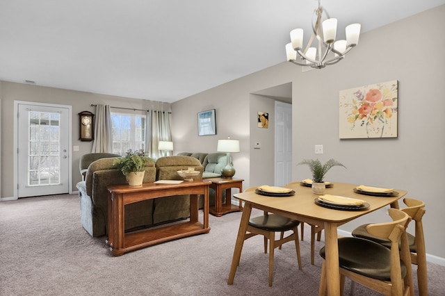 carpeted dining space featuring a chandelier and baseboards