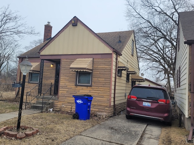 view of home's exterior featuring stone siding, roof with shingles, and fence