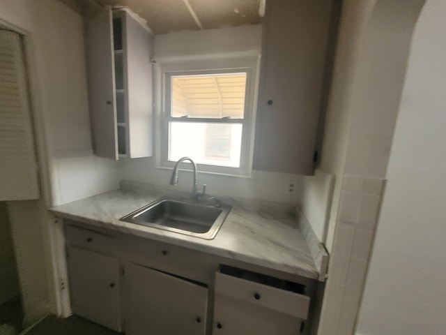 kitchen featuring light countertops, a sink, and white cabinets