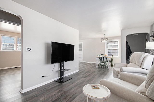 living area featuring baseboards, visible vents, arched walkways, and dark wood finished floors