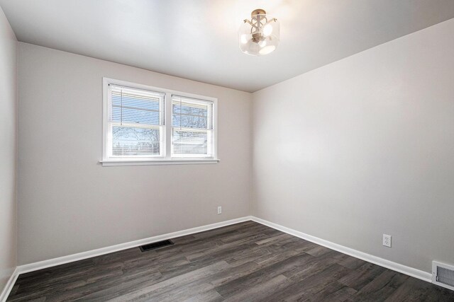 empty room featuring baseboards, visible vents, and dark wood-style flooring