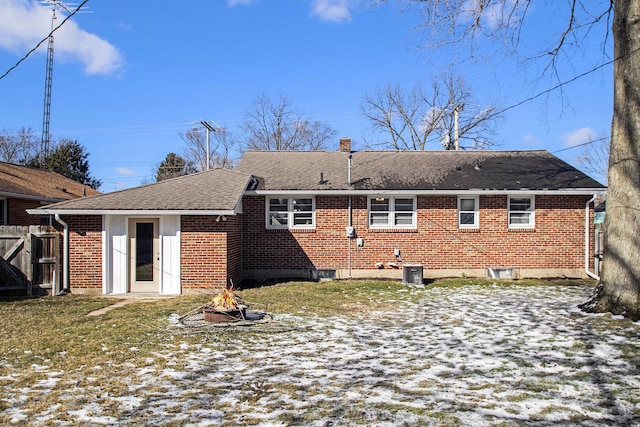 rear view of house with central air condition unit, brick siding, fence, roof with shingles, and a chimney