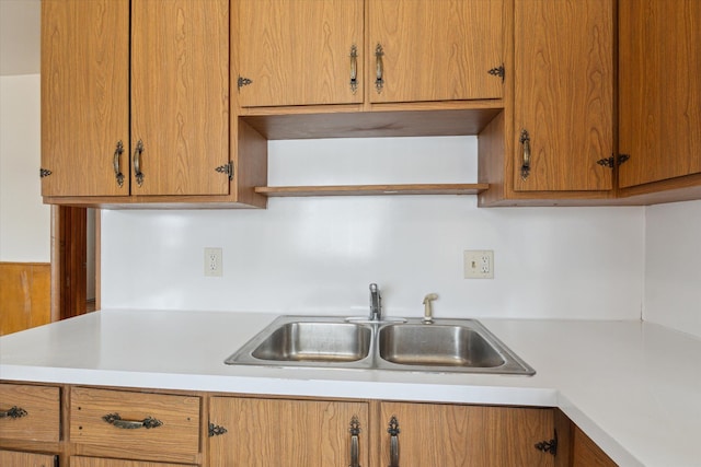 kitchen featuring light countertops, open shelves, and a sink