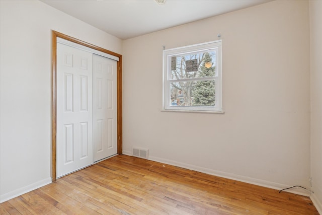 unfurnished bedroom featuring light wood-style floors, a closet, visible vents, and baseboards