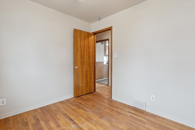 spare room featuring light wood-style flooring, visible vents, and baseboards