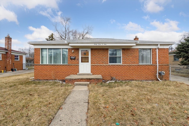 view of front of property with brick siding, a chimney, a front yard, and fence