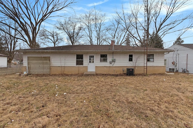 view of front of property with central air condition unit, a front yard, a chimney, and an attached garage