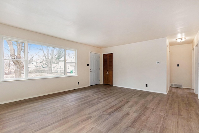 empty room featuring visible vents, baseboards, and light wood-style floors