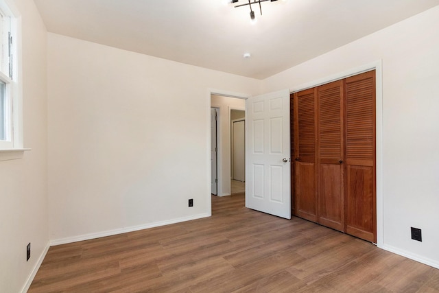 unfurnished bedroom featuring a closet, baseboards, and light wood-style flooring