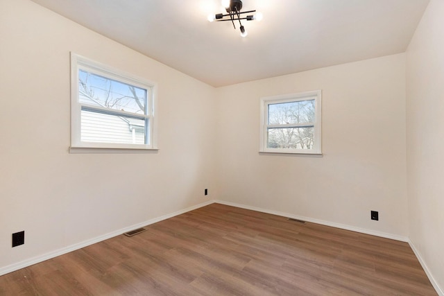 empty room with visible vents, plenty of natural light, and wood finished floors