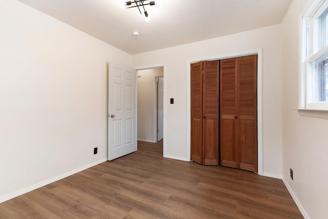 unfurnished bedroom featuring a closet, baseboards, and wood finished floors