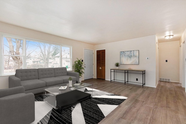 living room featuring wood finished floors, visible vents, and baseboards