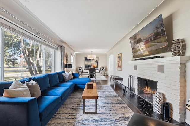 living room featuring dark wood-type flooring, a fireplace, and arched walkways