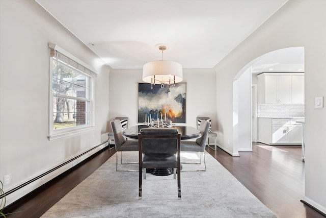 dining space featuring dark wood finished floors, baseboards, arched walkways, and a baseboard radiator