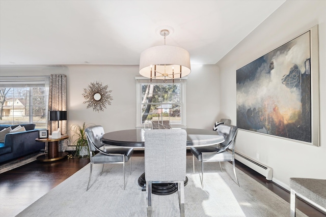 dining space with a wealth of natural light, a baseboard heating unit, and wood finished floors