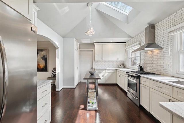 kitchen with dark wood finished floors, wall chimney exhaust hood, light stone countertops, and appliances with stainless steel finishes