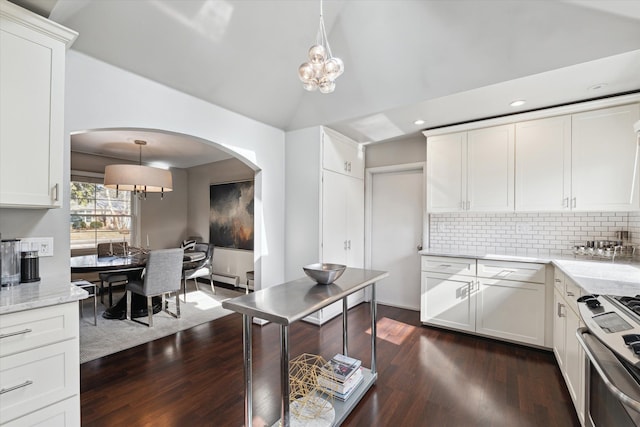 kitchen with lofted ceiling, white cabinets, dark wood-style floors, and stainless steel gas range oven