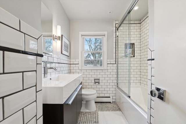 bathroom with a healthy amount of sunlight, tile walls, a baseboard heating unit, and toilet